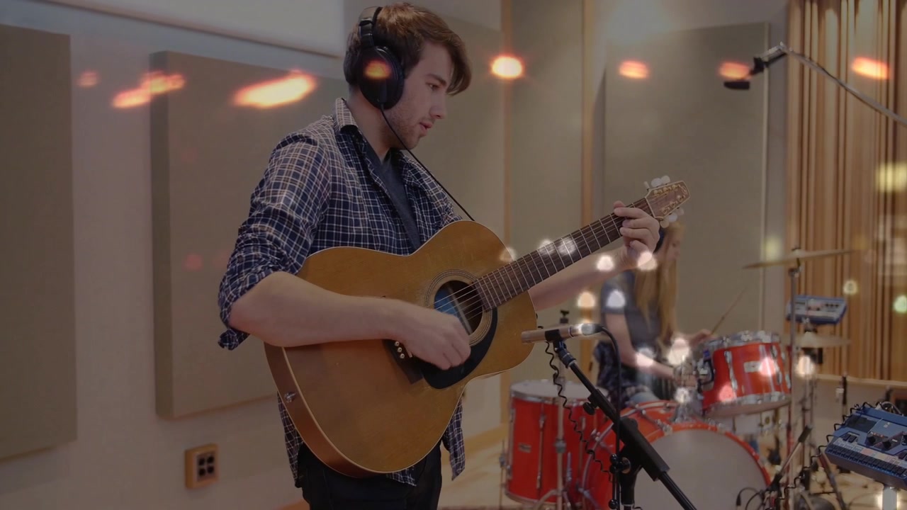 Hombre rasgueando la guitarra y mujer tocando la batería en un estudio de grabación con ondas de sonido animadas.