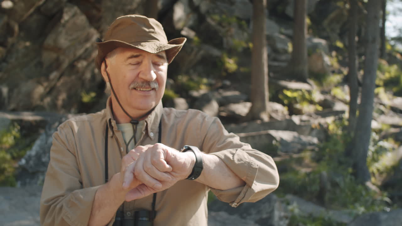 hombre mayor comprobando el reloj en la naturaleza