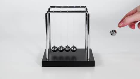 human hand interacting with a newton's cradle