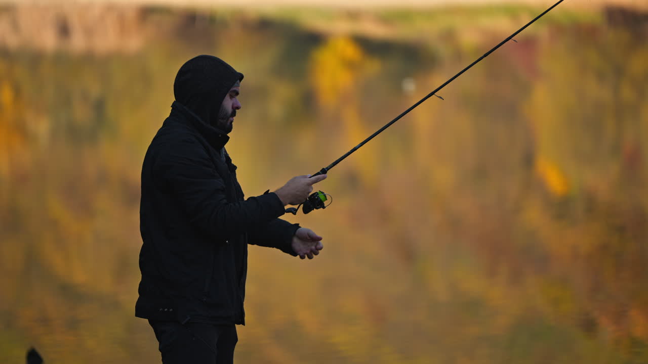 Seorang pemancing sedang memancing di danau di musim gugur