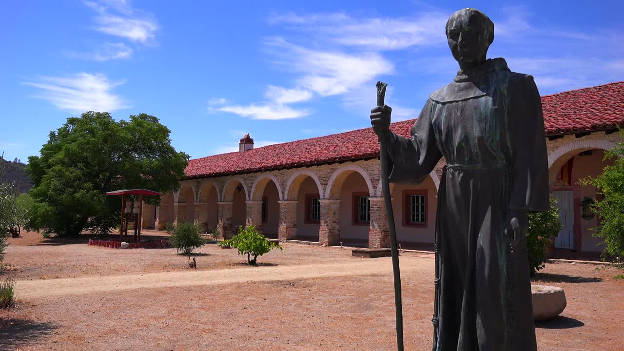 una estatua del padre junipero serra se encuentra frente a una misión de california 1