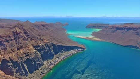 High-Aerial-View-of-Majestic-Island-Cut-with-Scenic-Cliffs-and-Colorful-Waterway-near-Beach-Point