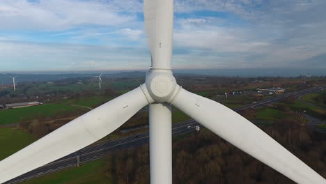 Drohneninspektion-Der-Vorderen-Rotorblätter-Einer-Windkraftanlage-Aus-Der-Luft-Und-Verfolgung-Der-Rückseite-Mit-Der-Autobahn