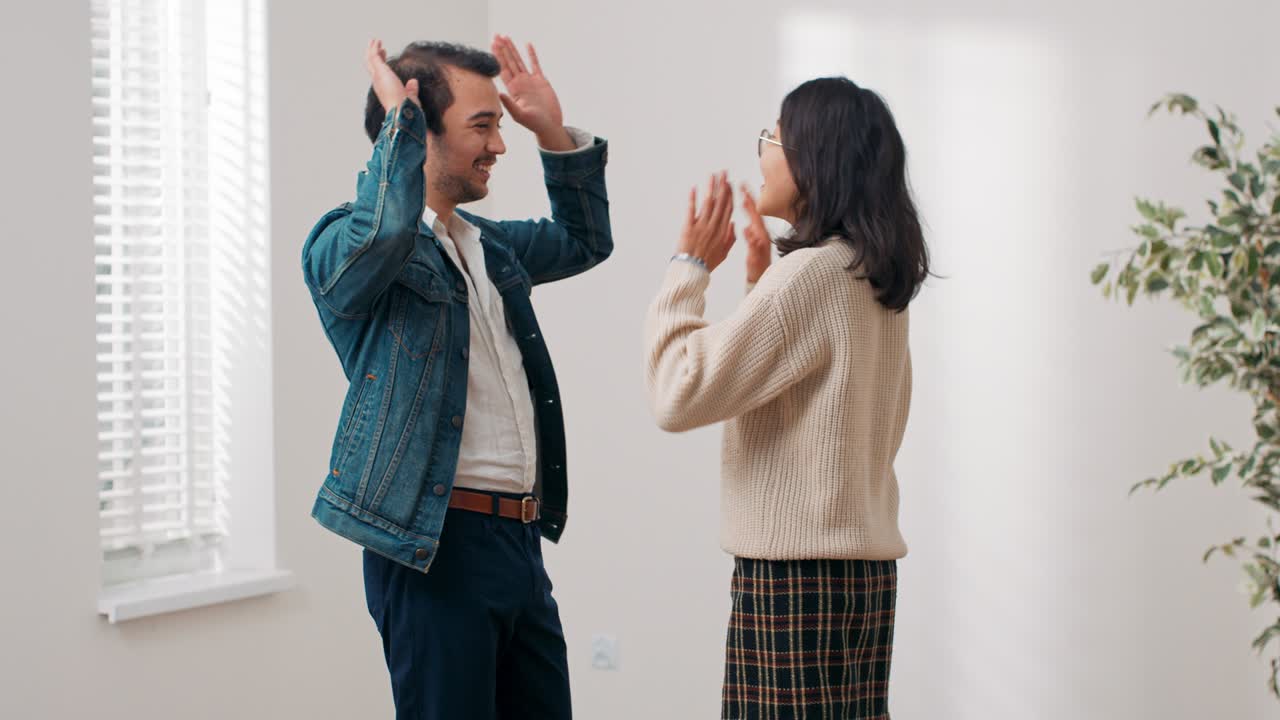 결혼한 부부는 새로 구입한 아파트로 이사하고, 그들은 집을 임대하여 행복합니다, 그들은 하이 파이브 포옹, 남자는 기과 행복으로 여자를 들어 올립니다.