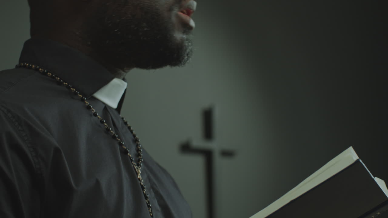 Black Priest Reading Bible and Leading Congregation in Prayer