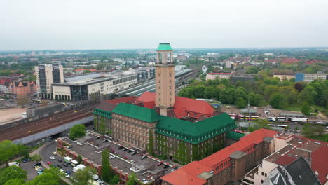 Fly-around-tall-tower-of-Rathaus-Spandau.-Historic-building-of--town-hall-of-Spandau-borough.-City-with-train-station-in-background.-Berlin,-Germany