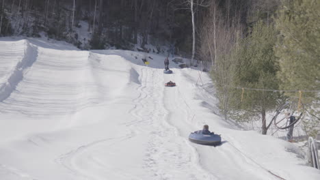 Tubos-De-Nieve-Para-Niños,-Remolque-De-Cuerda-Cuesta-Arriba-En-Un-Día-Soleado-De-Invierno