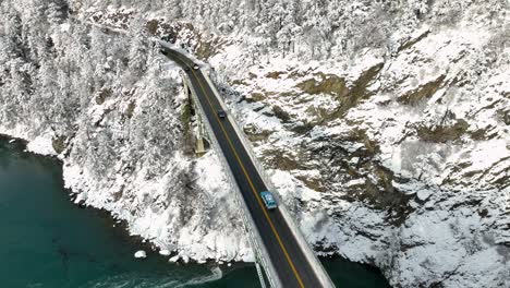 drone shot of cars driving over onto the mainland covered in snow