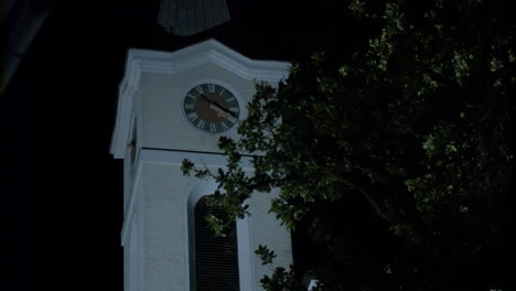 Church-tower,-clock-tower-at-night,-with-a-tree-in-front