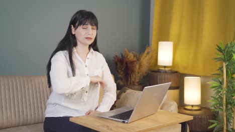 woman looking tired and exhausted at laptop at night.