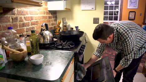 hombre se quema la mano al intentar sacar algo del horno.