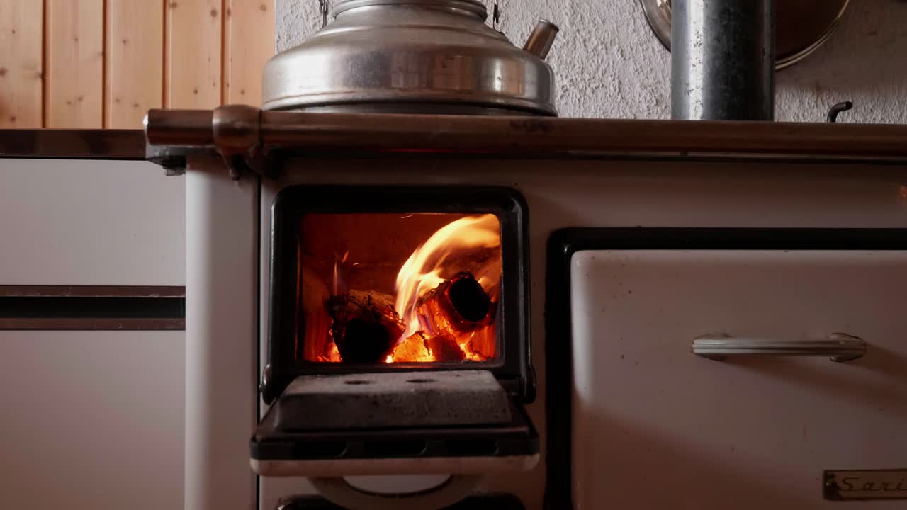 A wood-burning stove with flames inside, used in an old Swiss house for heating