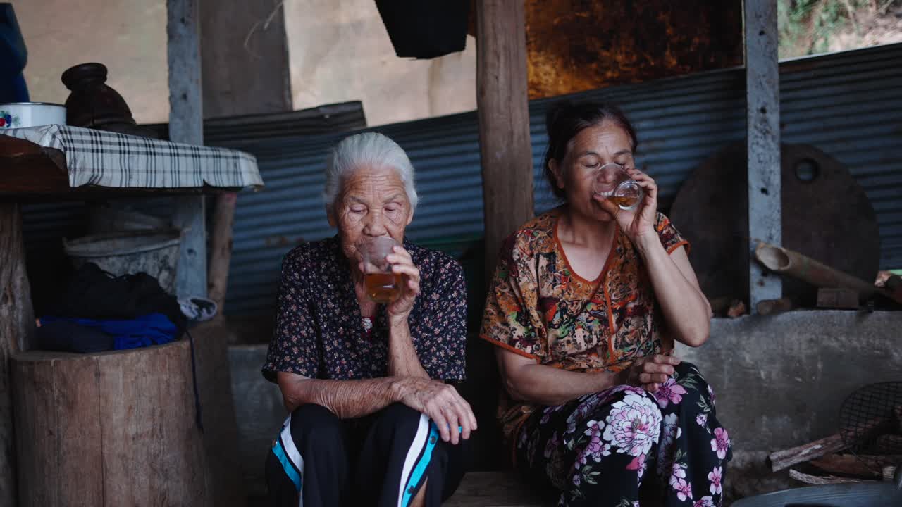 Two elderly women drinking tea indoors