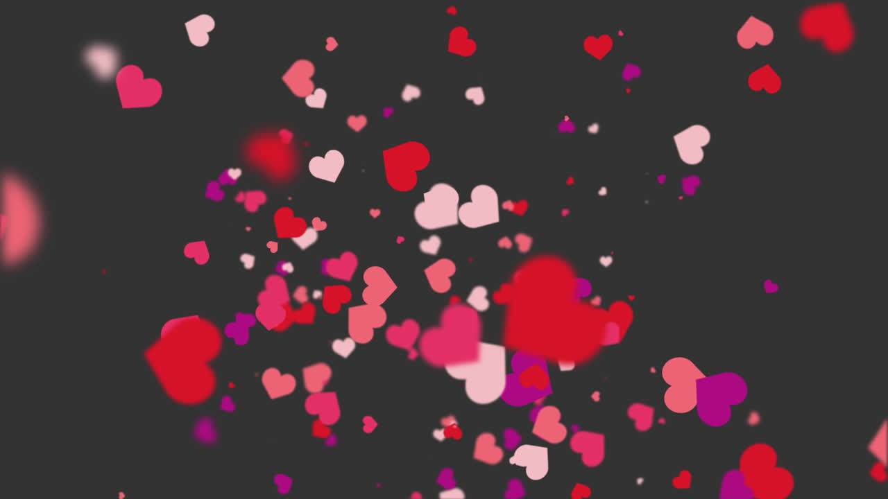 Freely falling down colored figures of hearts. Animated abstract dark gray background. Looped video. Concept for valentine's day, wedding.