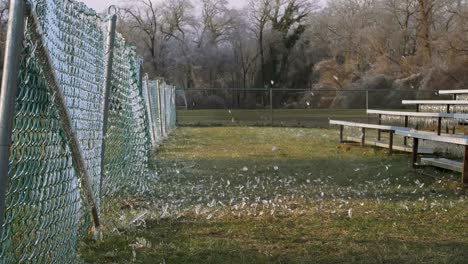 slow motion: een zijaanzicht van een voetbal die tegen een ijzig hek slaat waardoor het verbrijzelde ijs de lucht in explodeert