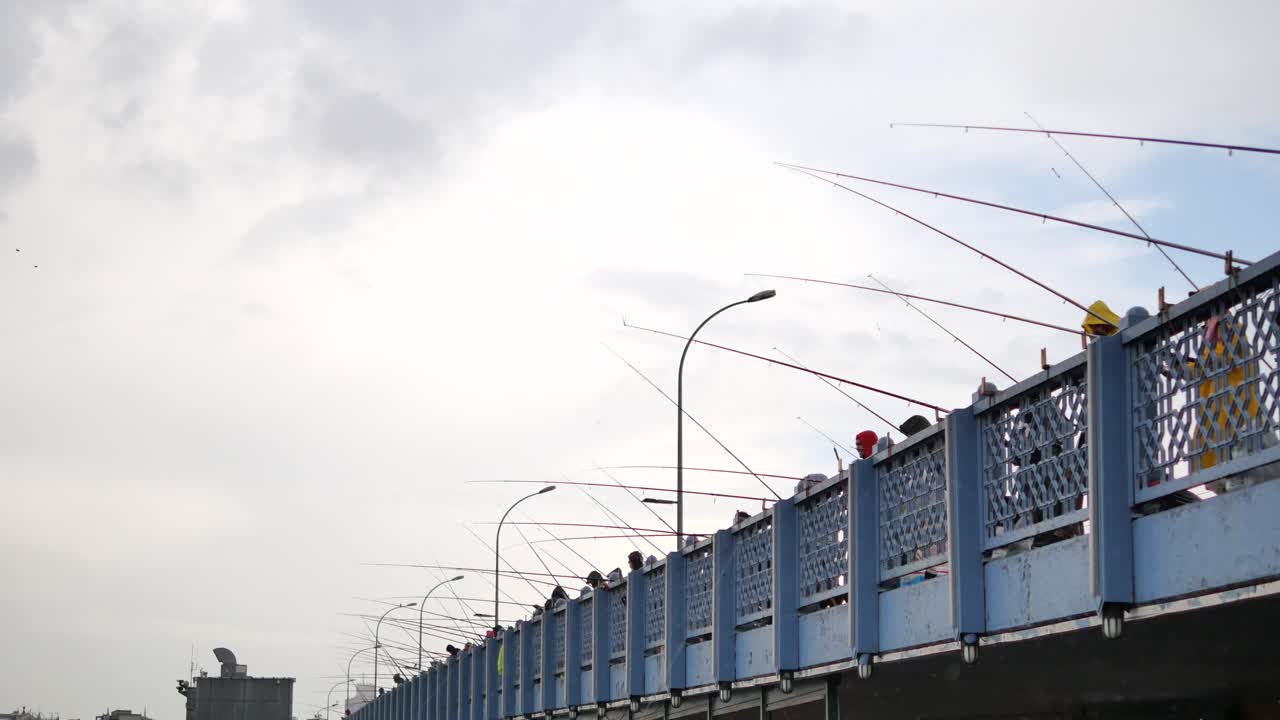 personas pescando desde un puente en un día nublado