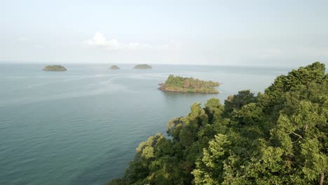 aerial-shot-of-rainforest-with-ocean-and-islands-in-the-distance,-Koh-Chang,-Thailand,-shot-at-sunrise