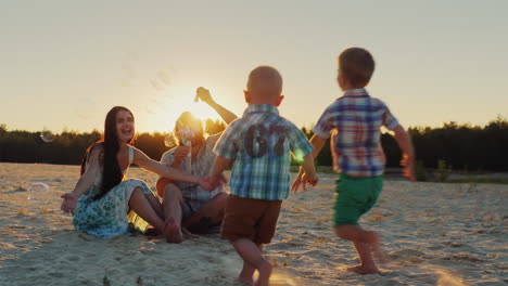 young family having fun with kids - blow bubbles at sunset