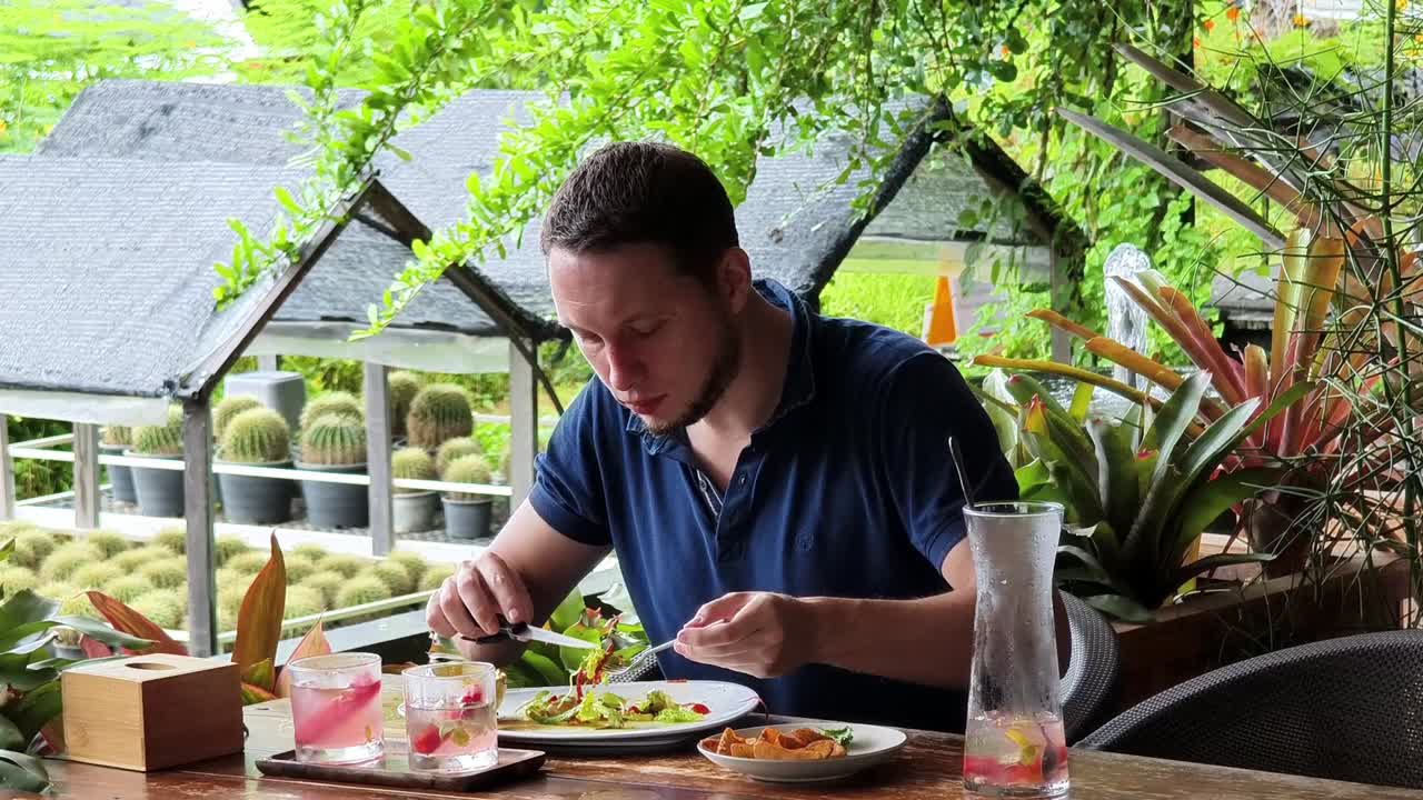 hombre comiendo almuerzo en un restaurante de jardín tropical