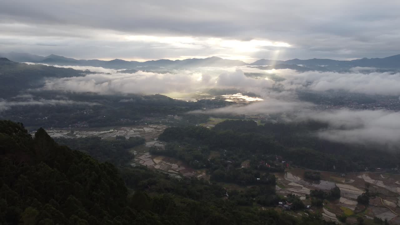 Sun Rays Piercing Through Clouds Over a Mountain Valley Landscape