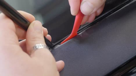 plastic tool pushing car wrapping vinyl into car's exterior seam