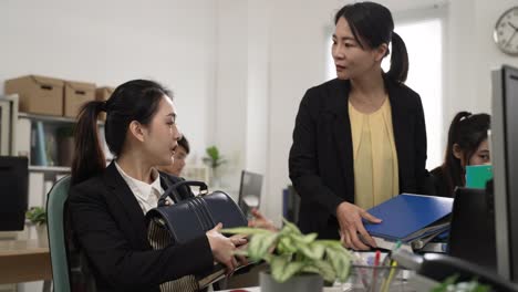 asian woman employee saying no to boss’s request for more jobs and getting off work in a hurry. upset female manager holding piles of paperwork and shaking head