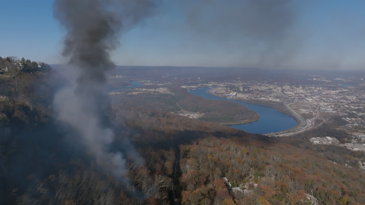 Static aerial footage of a forest fire on Lookout Mountain burning with Chattanooga and the Tennessee River in the background.