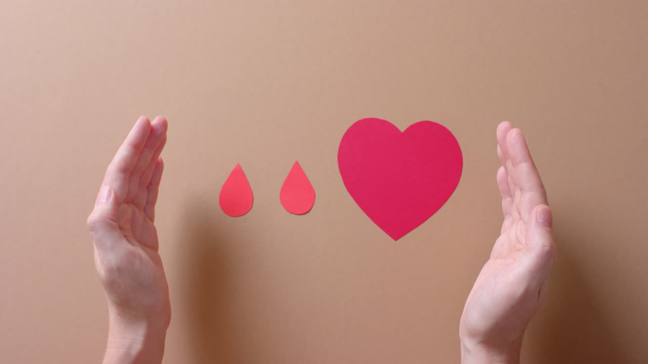 de manos de hombre caucásico sobre el corazón y gotas de sangre en fondo beige, cámara lenta