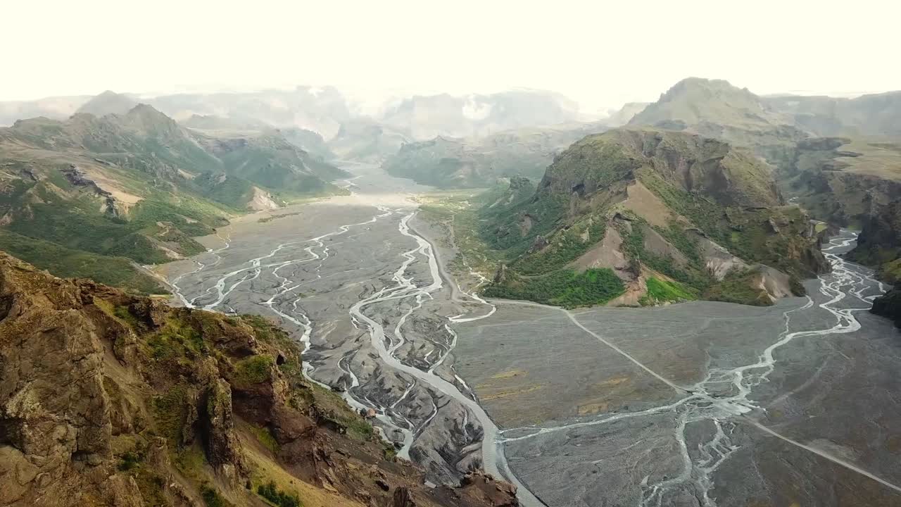 Winding through the Þórsmörk valley, the Krossá river creates stunning scenery, framed by majestic rhyolite mountains of Iceland, showcasing the region's breathtaking natural beauty, drone reveal shot