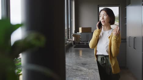 아시아 여성이 주방에서 혼자 스마트폰으로 대화하고 있다.