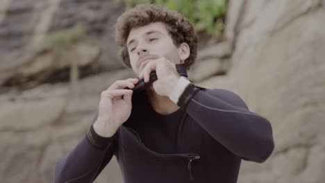 man putting on wetsuit for water sports