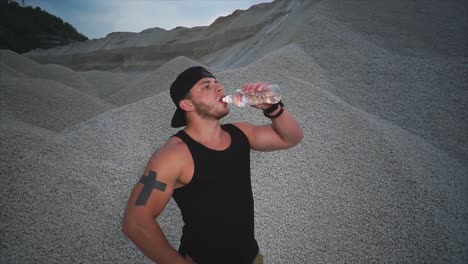 muscular man drinking water in a quarry