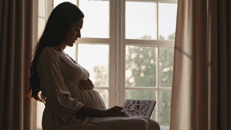 mujer embarazada leyendo por la ventana