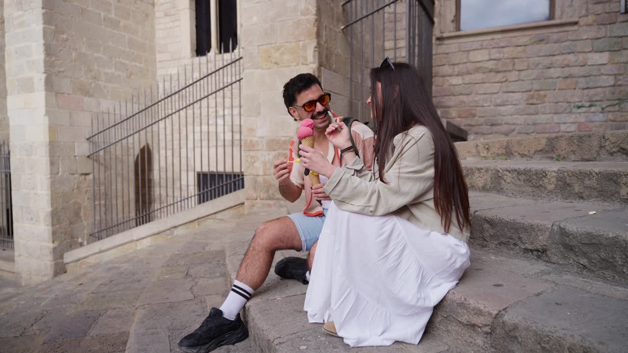 Giovane coppia felice che mangia un gelato e chiacchiera sui gradini della città