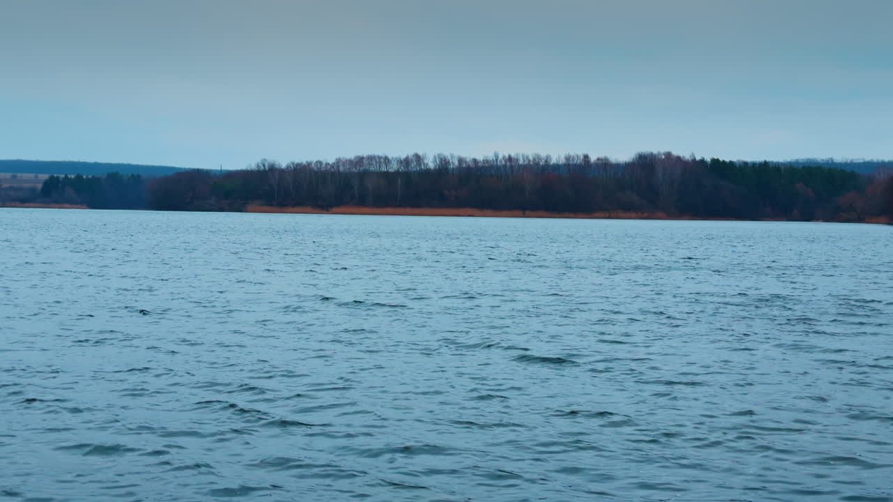 Cold late autumn day on the big river. Grey waterscape reflecting overcast skies above.