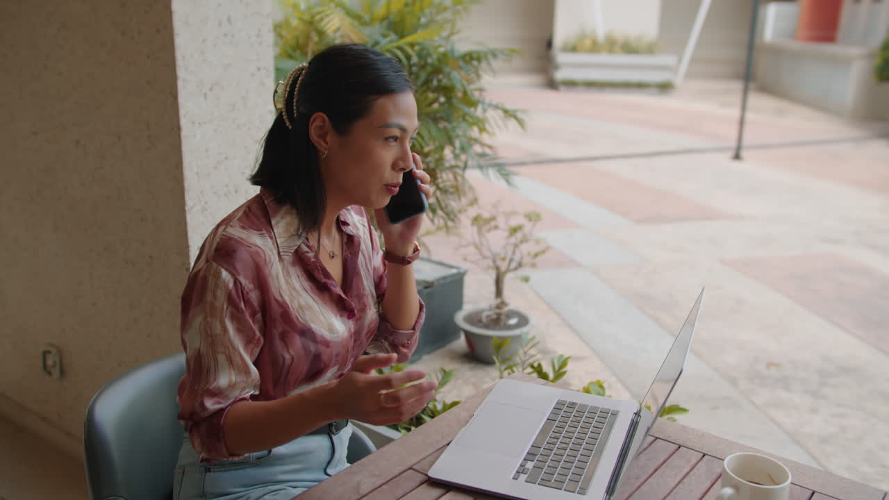 Young Businesswoman Consulting on Smartphone at Cafe Terrace