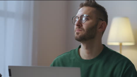 Retrato-De-Un-Hombre-Pensativo-Con-Gafas-Frente-A-Una-Computadora-Portátil-En-Casa,-Un-Escritor-De-Periodista-Está-Pensando-En-Un-Trabajo-Independiente-Y-Creativo