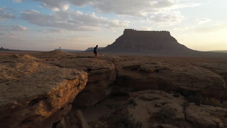 un hombre corriendo en la cima de una colina rocosa al atardecer