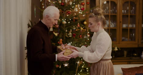 woman giving christmas present to grandfather at home 4