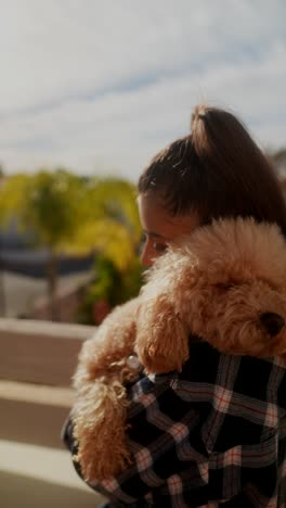 mujer sosteniendo un cachorro en un balcón