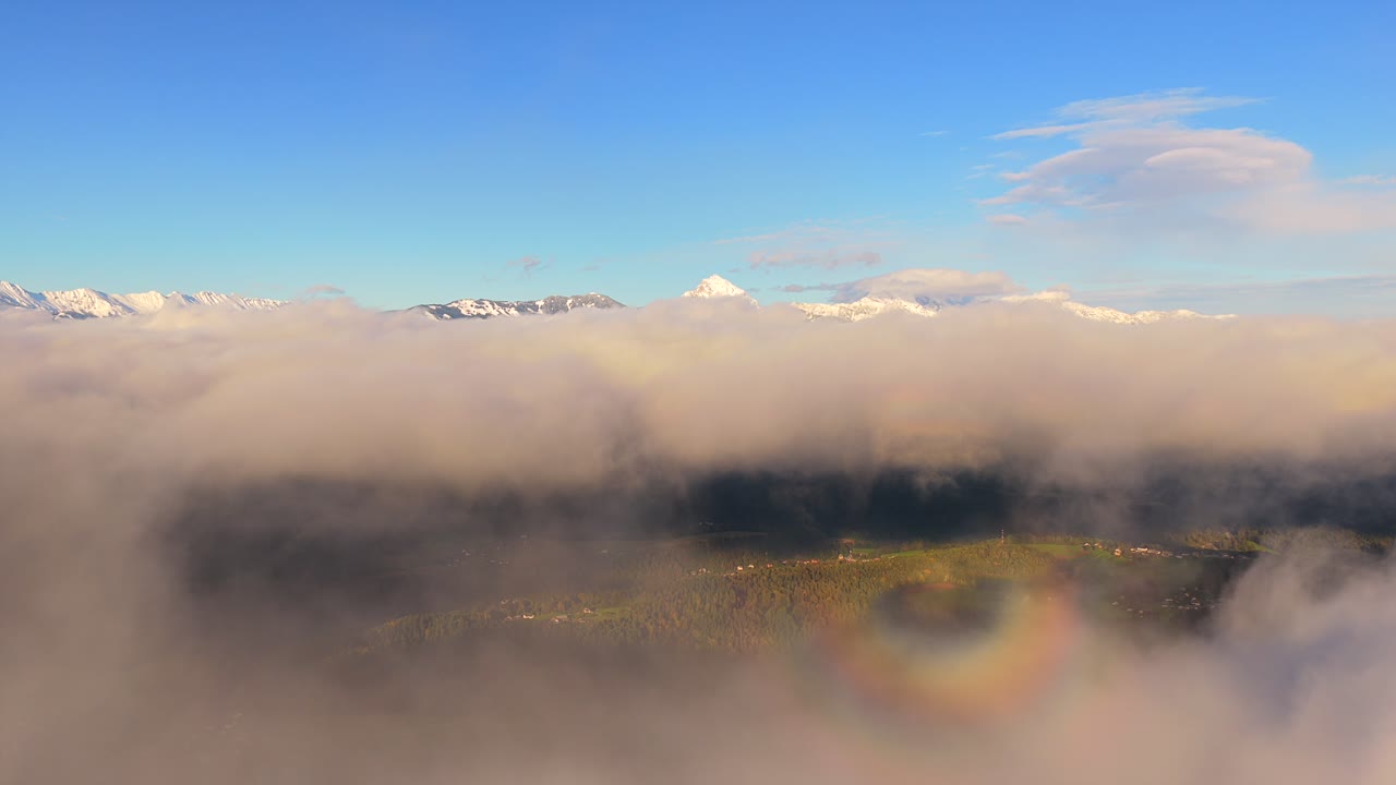 Aerial view over clouds with snowy mountain peaks, serene and majestic