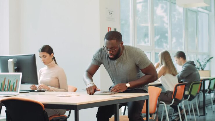 African man finishing work in coworking space. Concentrated man closing laptop.