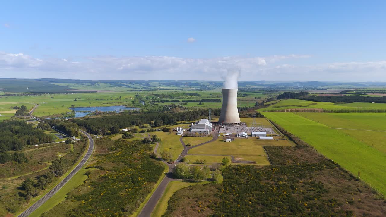 Torre de resfriamento expele vapor branco acima da usina geotérmica de Ohaaki em Waikato, Nova Zelândia, em plano de drone com órbita ampla à esquerda