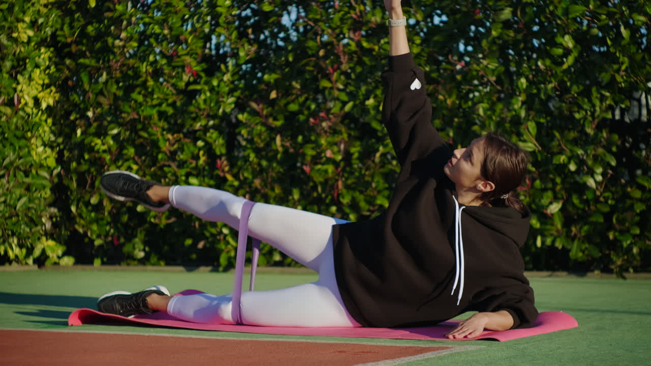mujer realizando un ejercicio de piernas de banda de resistencia afuera