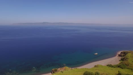 Aerial:-A-quiet-beach-with-a-fishing-boat-on-Lesbos,-near-Turkey