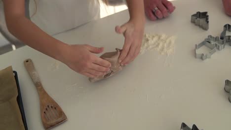 Closeup-young-girl-hands-kneading-dough-on-a-white-table-in-kitchen.-Healthy-food,-childhood,-family,-handmade,-hobby,-bakery-concept.-High-angle-view