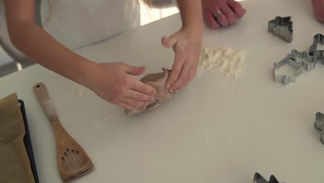 closeup young girl hands kneading dough on a white table in kitchen. healthy food, childhood, family, handmade, hobby, bakery concept. high angle view