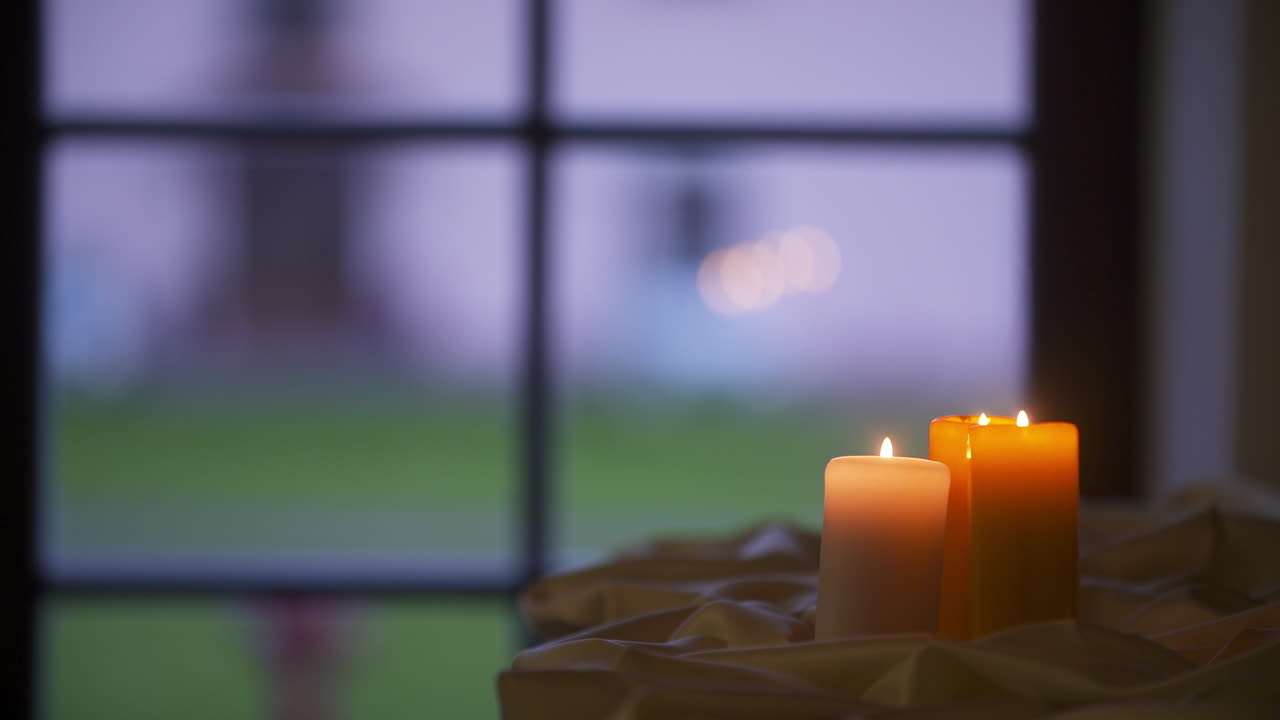 Lume di candela con una finestra sullo sfondo che simboleggia la speranza.