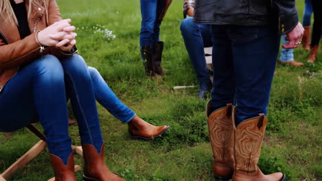 people in jeans and cowboy boots gathered in a grassy field