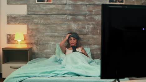 mujer en pijama asustada mientras ve la televisión